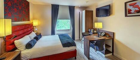 Habitación de hotel con cama, escritorio y televisor.