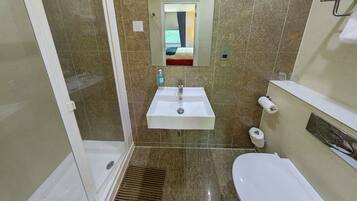 A bathroom with a shower, sink, toilet, and a mirror above the sink.