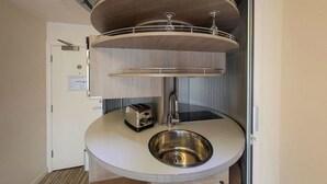 A compact kitchen with a sink, a toaster, and a hanging light fixture. - Simply Rooms & Suites (London)