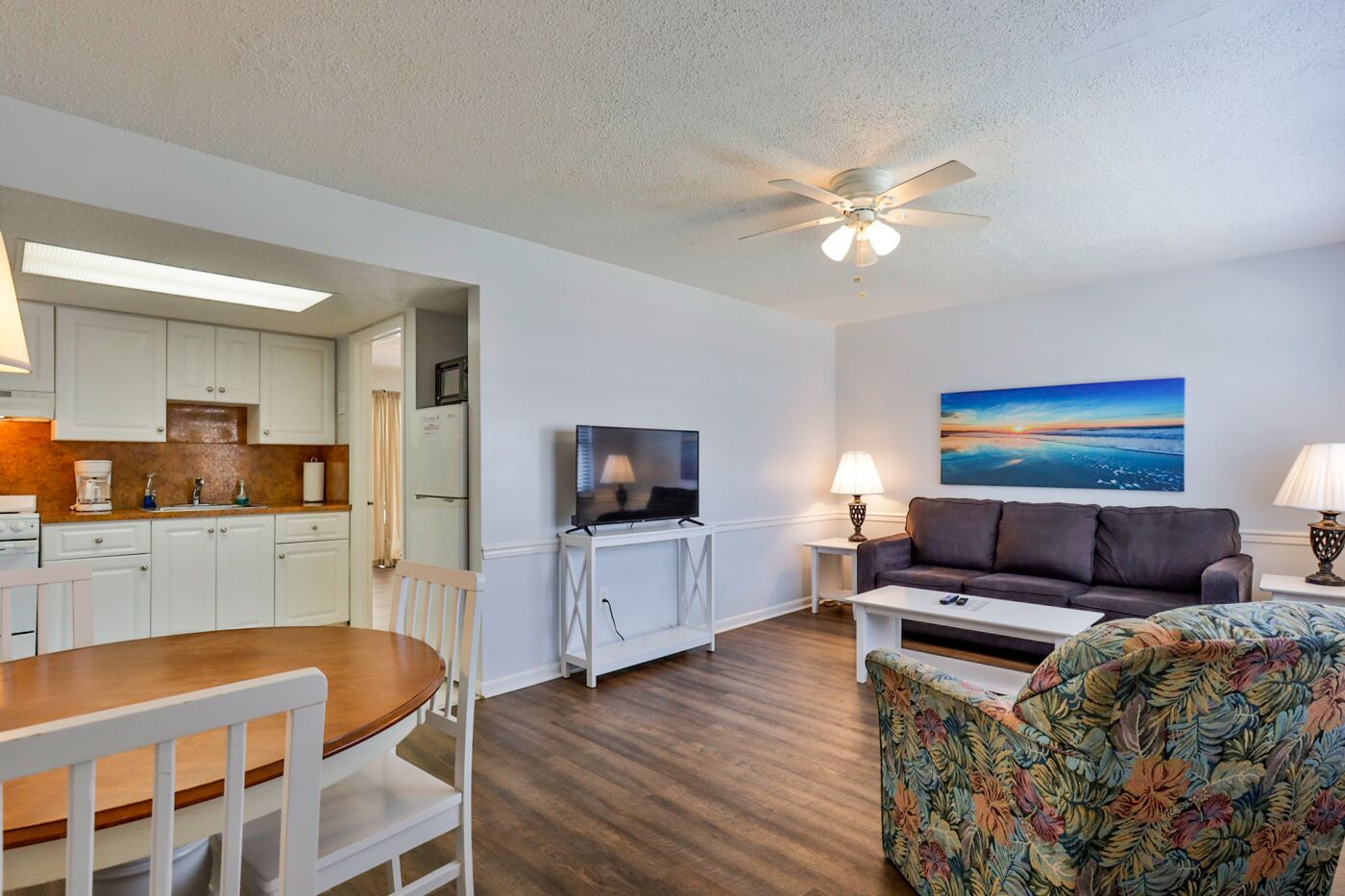 A compact living space with a kitchenette, a dining area, a sofa, and a television.