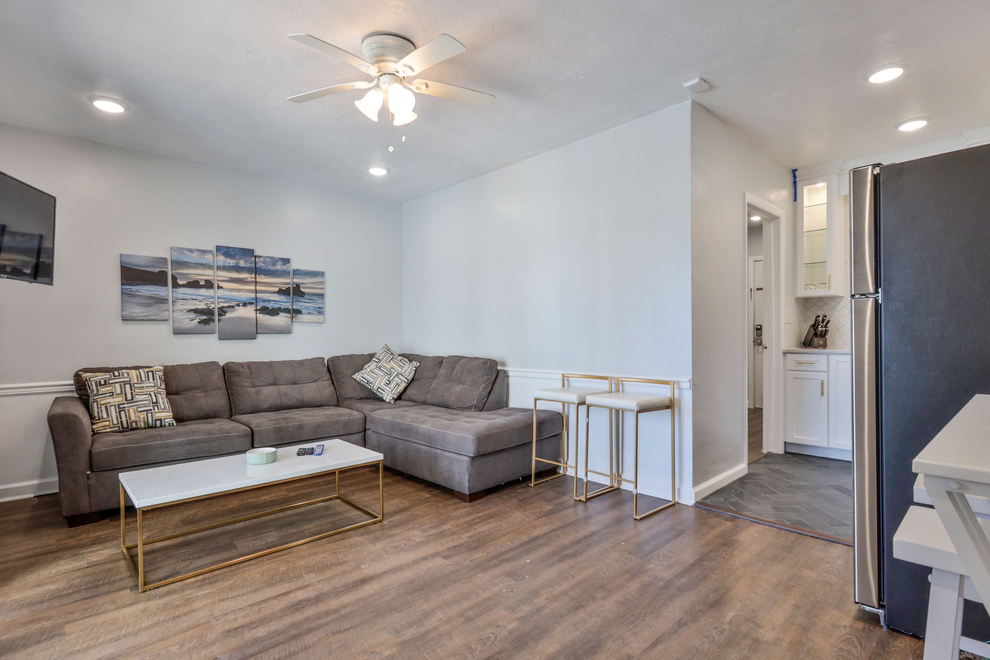 A modern living room with a sectional sofa, a coffee table, and a ceiling fan.