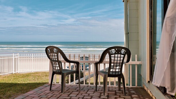A patio with two chairs and a table overlooking the ocean. - Coastal Waters Inn (New Smyrna Beach)