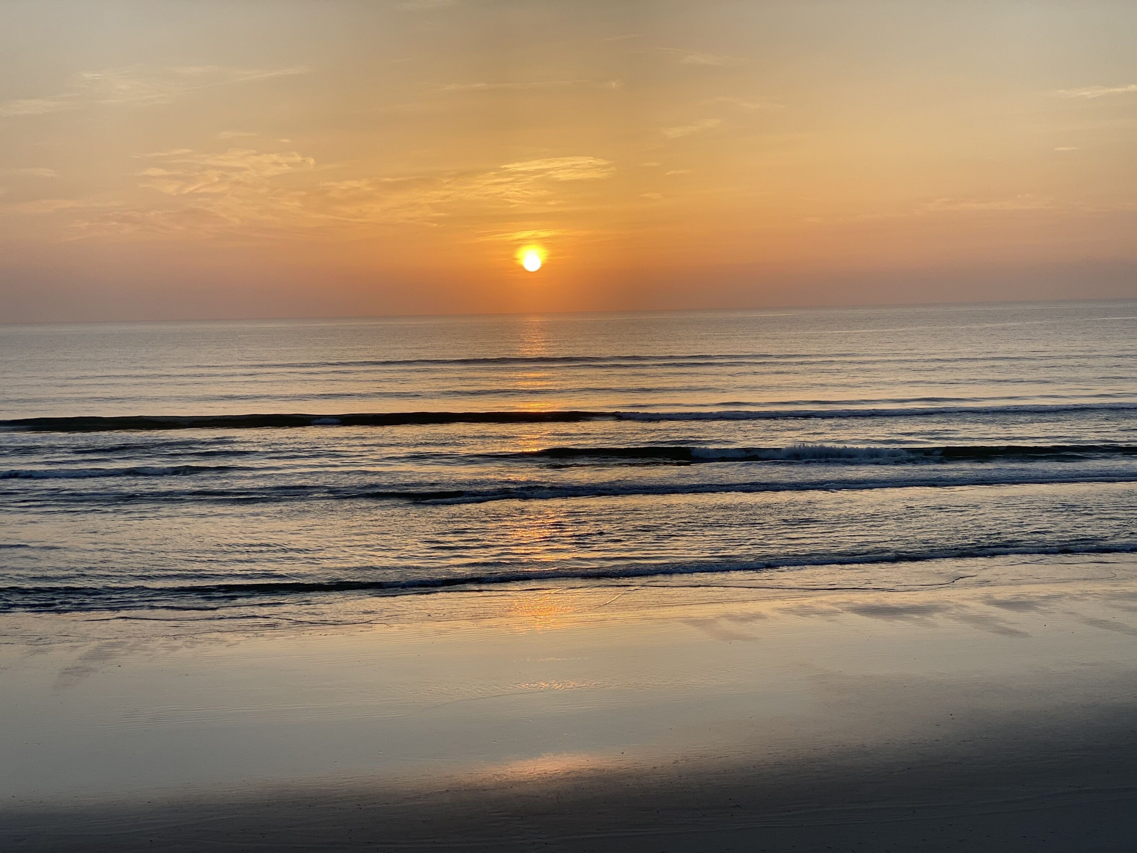 Una spiaggia con onde e un tramonto.