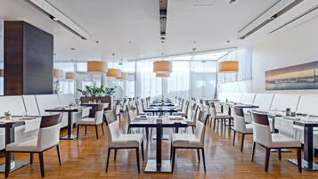 Un comedor amplio con mesas largas, sillas e iluminación colgante.