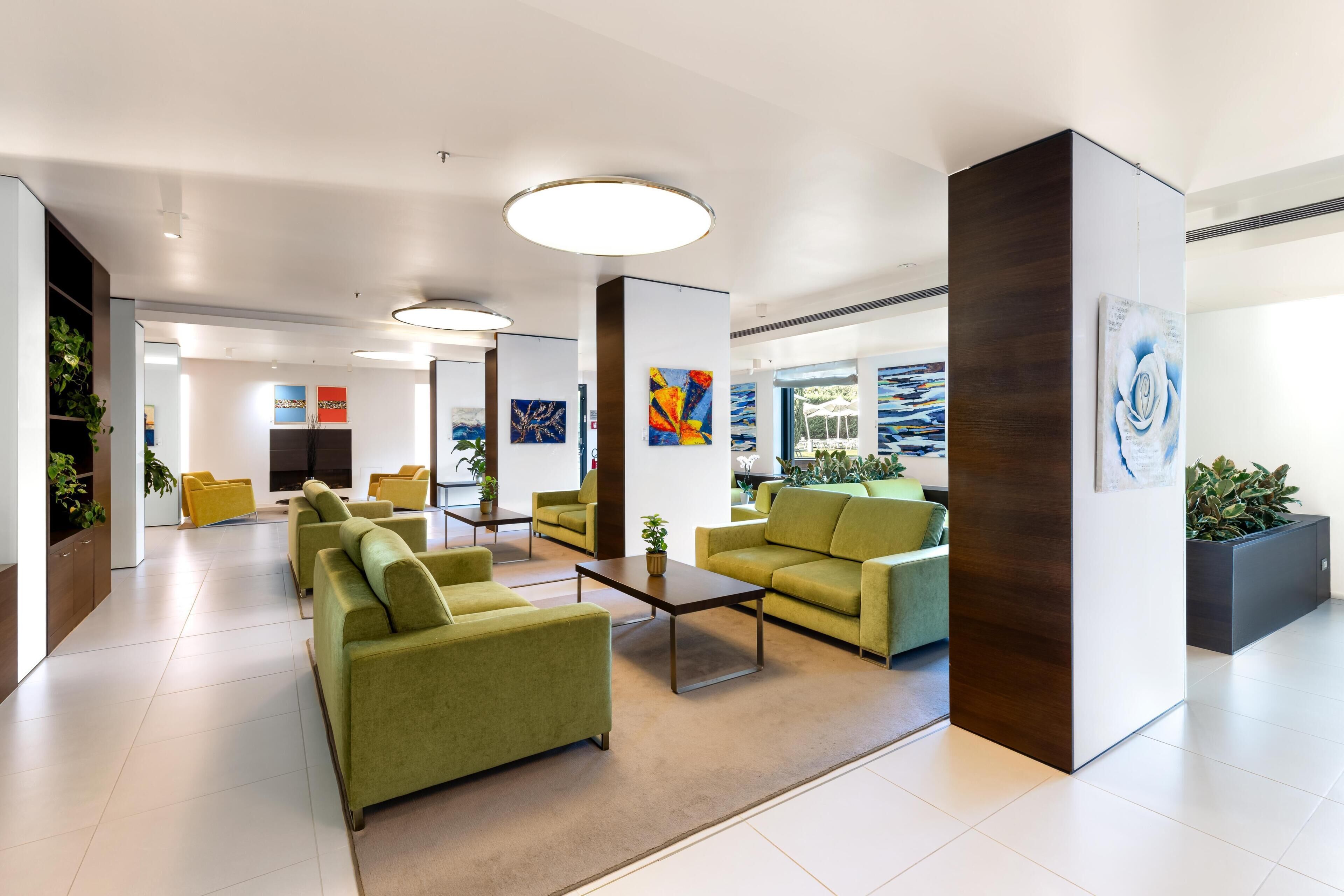 Eine moderne Lobby mit grünen Sofas, einem Couchtisch und Kunstwerken an den Wänden.