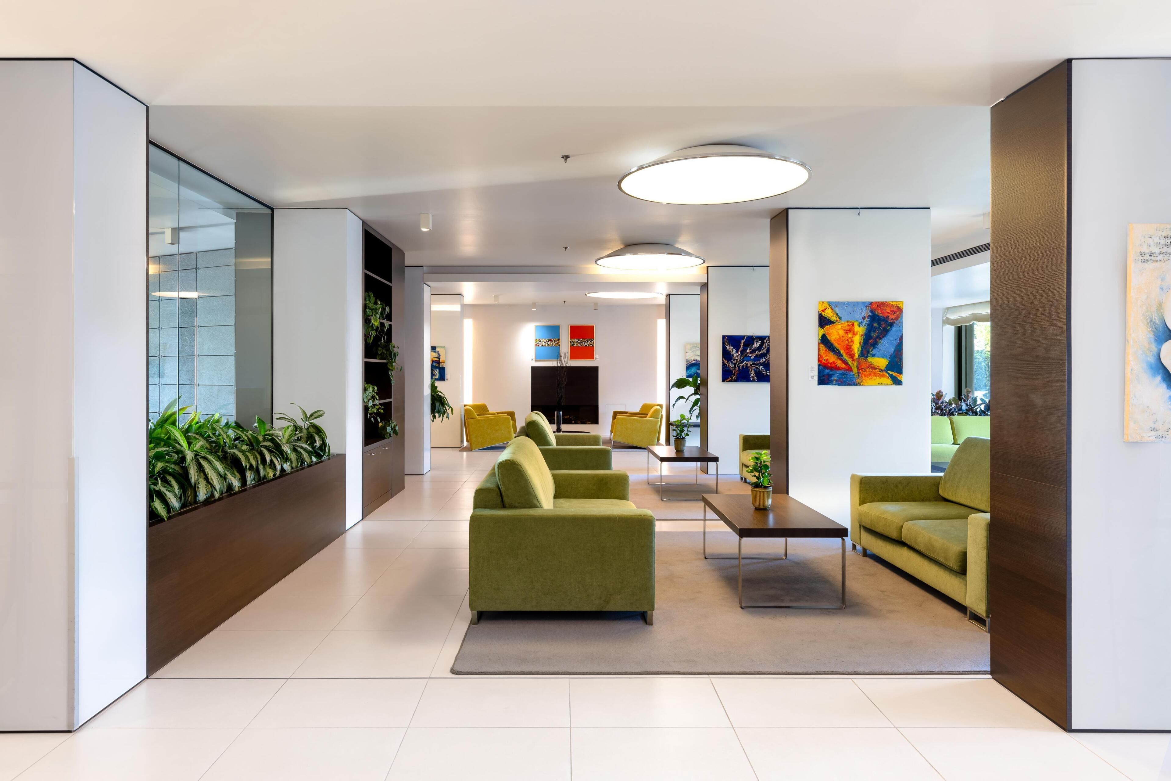 En moderne lobby med grønne sofaer, gule lænestole og kunst på væggene.