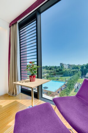 A room with a large window, a small table with a potted plant, and purple chairs. - Hilton Garden Inn Venice Mestre San Giuliano (Mestre)