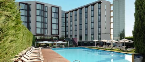 En säsongsöppen utomhuspool, parasoller och solstolar