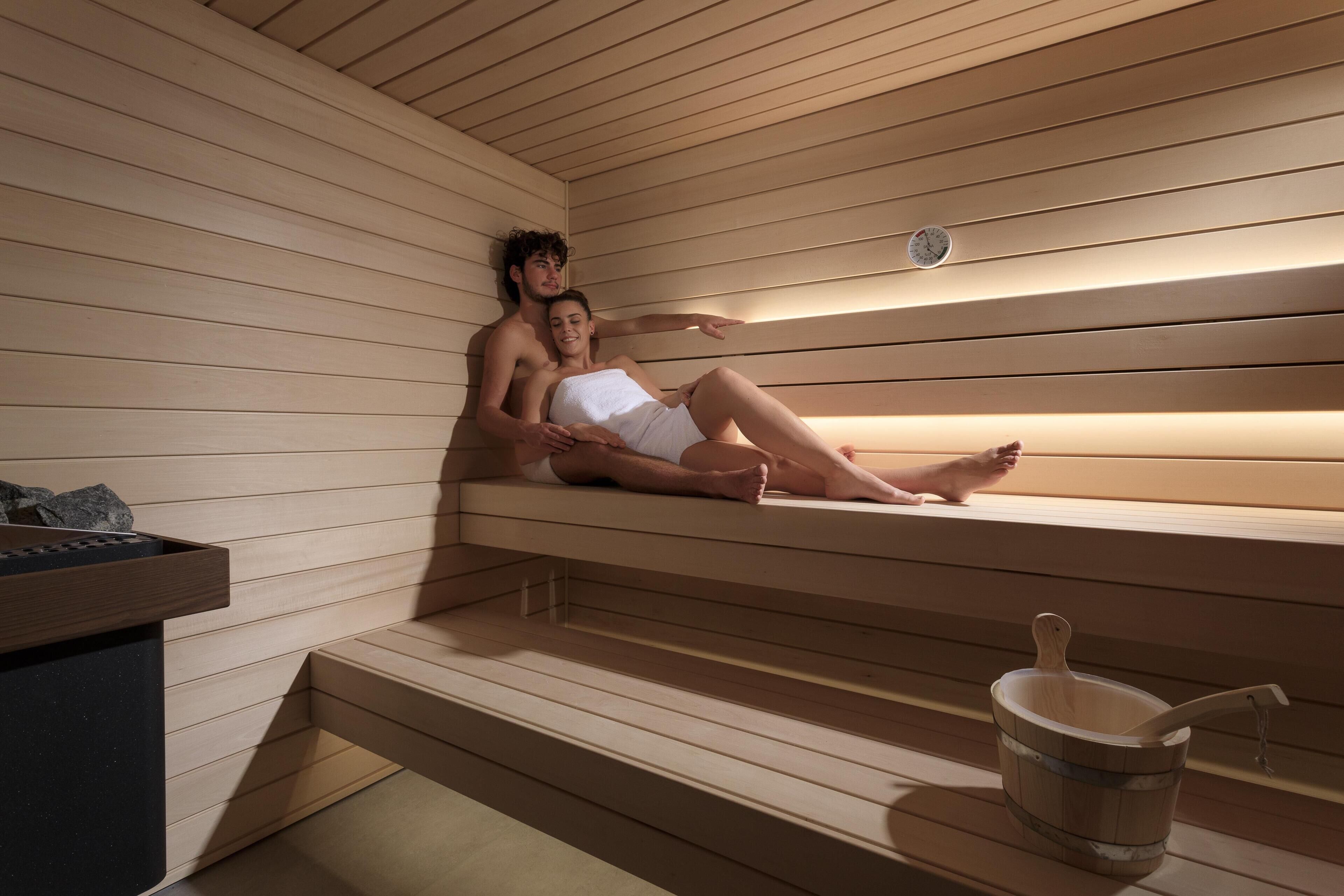 Een sauna met houten banken, een emmer en een klok aan de muur.