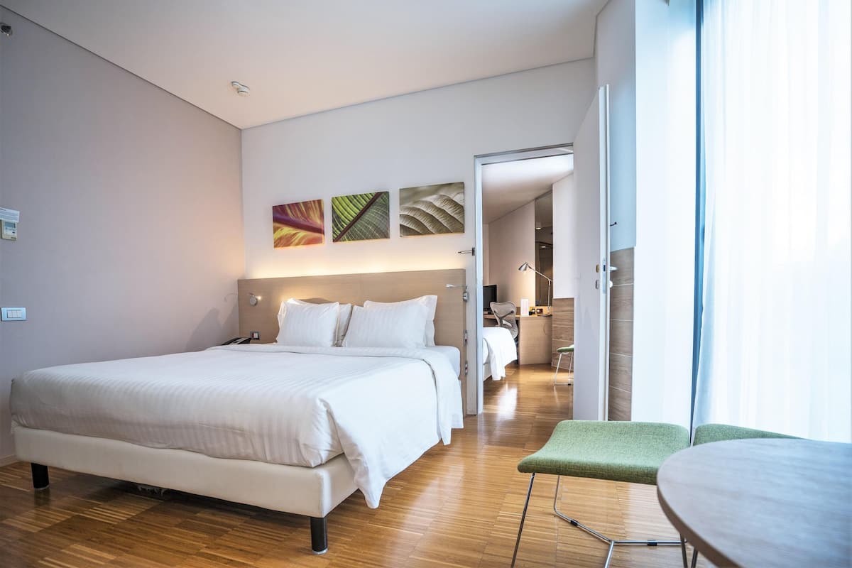 Una habitación de hotel moderna con una cama grande, un escritorio y una silla verde.