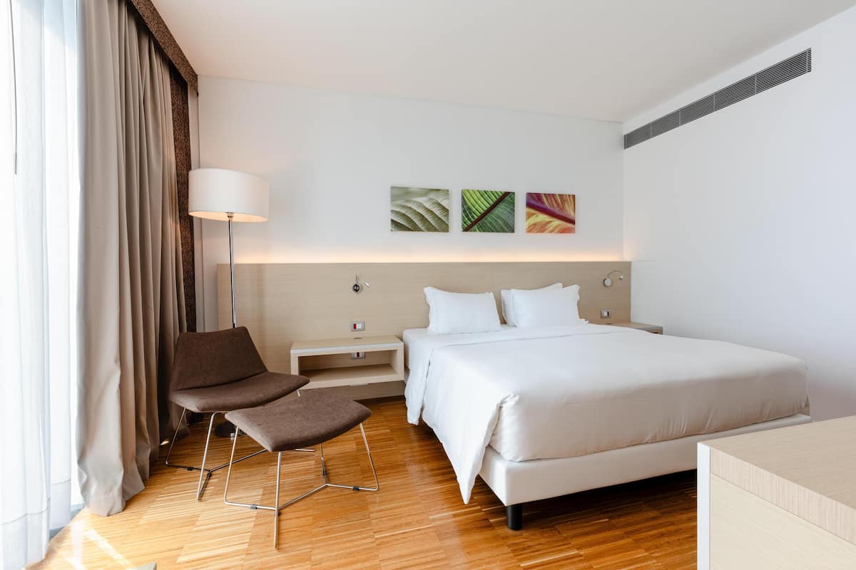 Habitación de hotel con cama, escritorio, silla, lámpara y obras de arte en la pared.