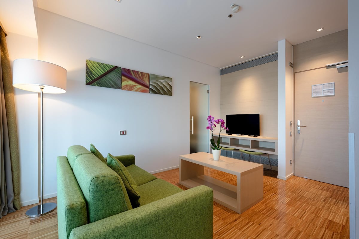 Una sala de estar moderna con un sofá verde, una mesa de centro, un televisor de pantalla plana y obras de arte en la pared.