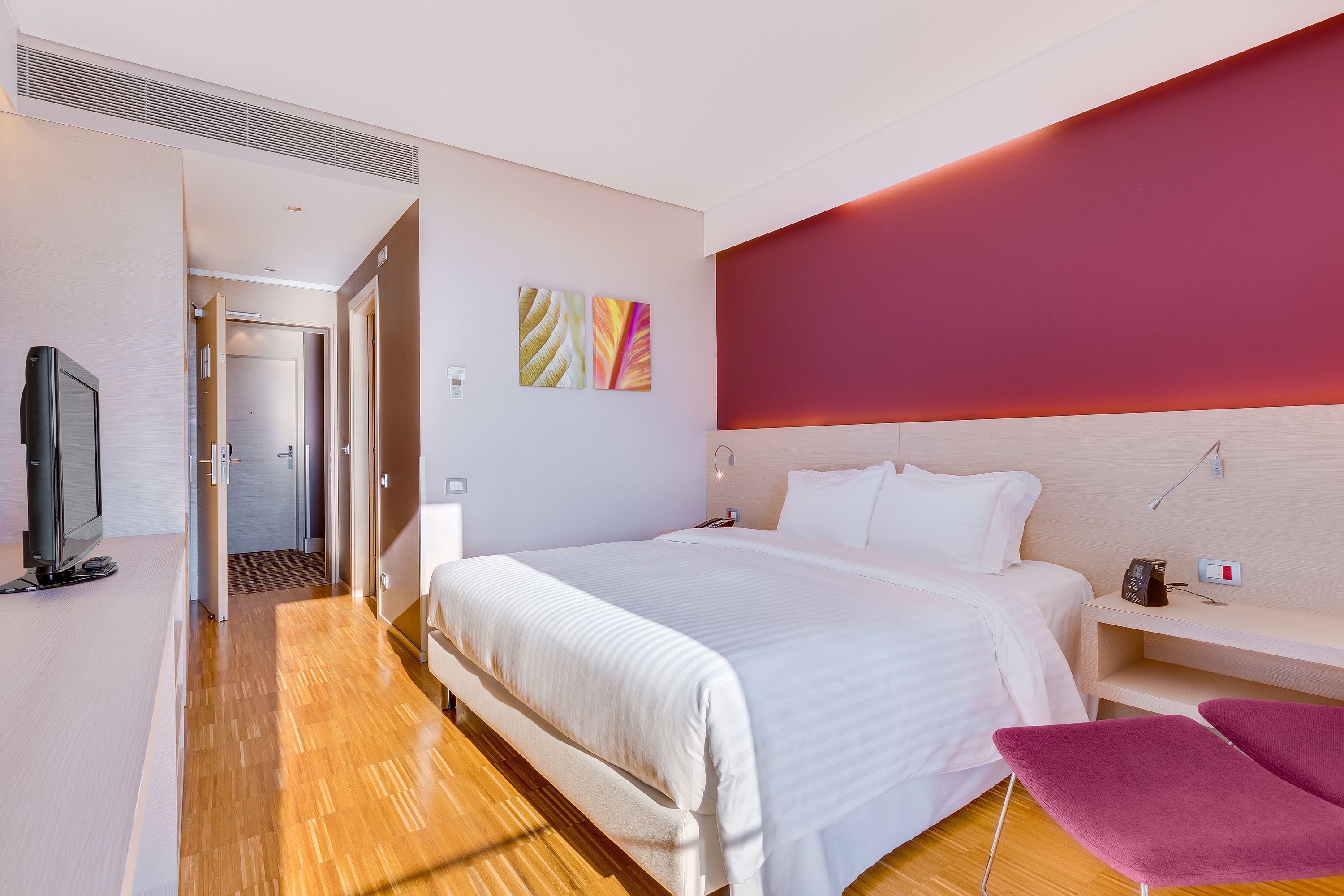Une chambre d’hôtel moderne, dotée d’un grand lit, d’un bureau et d’une télévision.