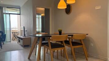 A dining area with a table and chairs, a clock on the wall, and pendant lights.