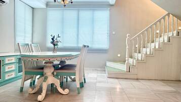 A dining area with a round table, chairs, and a chandelier. A staircase is visible to the right.