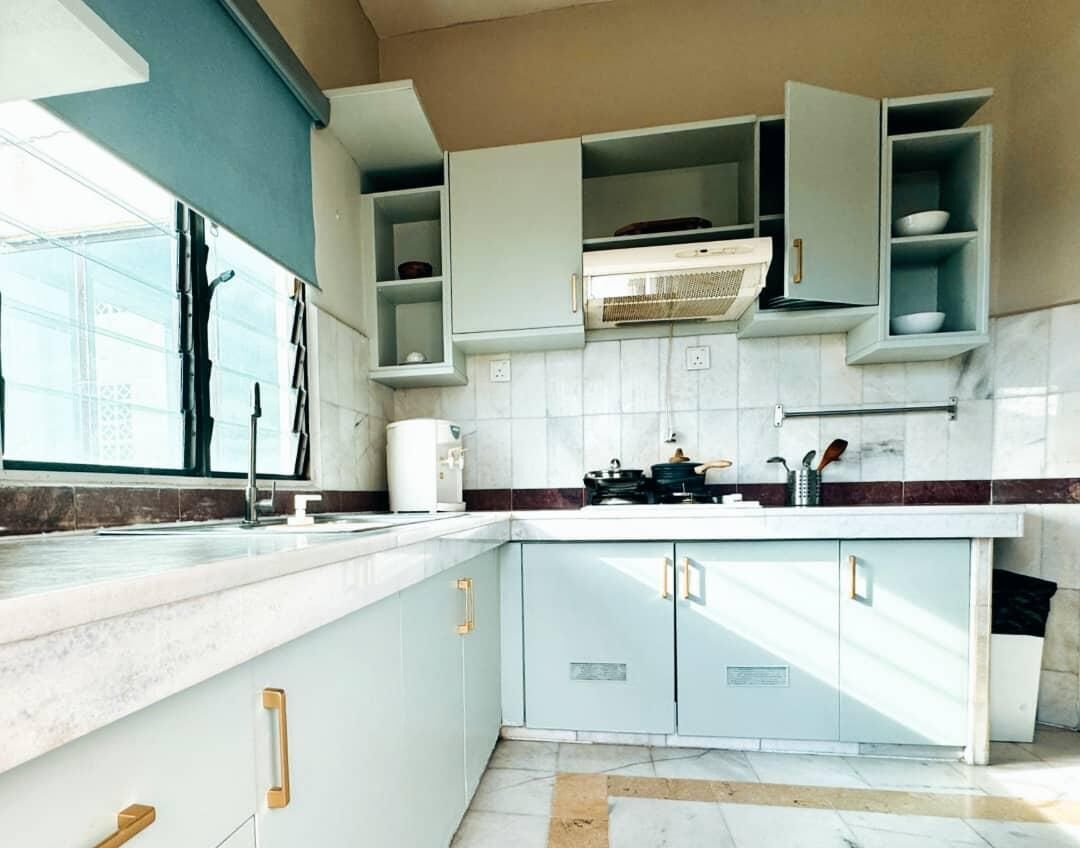 Eine moderne Küche mit hellblauen Schränken, einer weißen Arbeitsplatte und einem Fenster für natürliches Licht.