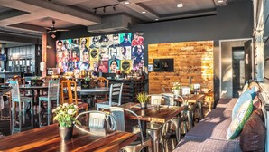 A modern cafe with wooden tables, metal chairs, and a colorful mural on the wall. - Century Bay Private Residences (George Town)