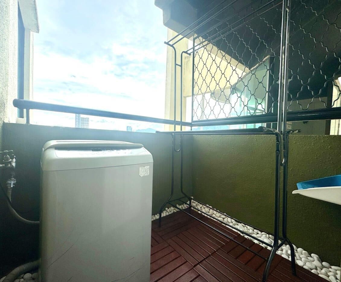 A balcony with a white appliance, a metal railing, and a view of the cityscape.
