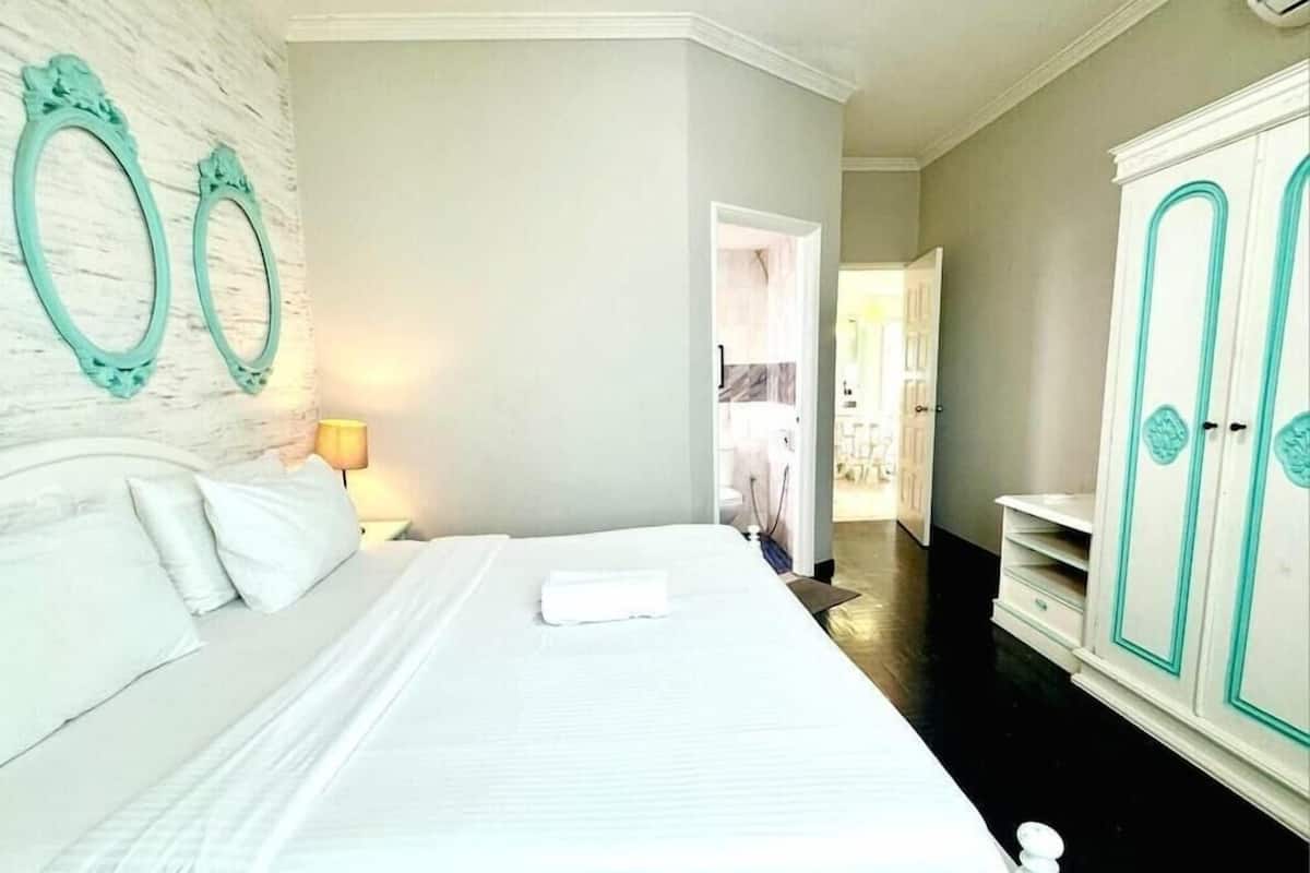 A hotel room with a large bed, a wardrobe, and a bathroom visible through an open door.