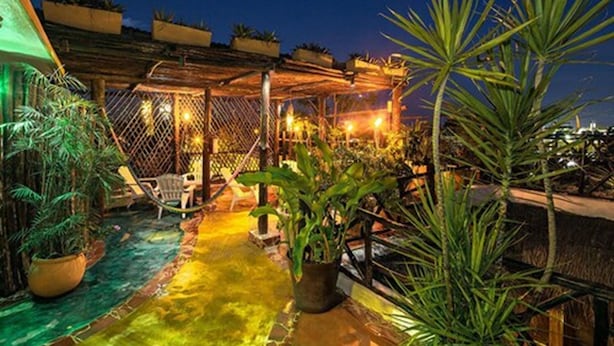 An outdoor patio area with a wooden pergola, seating, and potted plants. - Maison Tulum (Tulum)