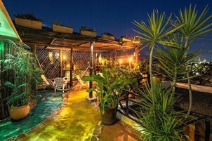 Un patio al aire libre con una pérgola de madera, asientos y plantas en macetas.