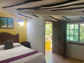 A bedroom with a bed, a nightstand, a wall-mounted lamp, and a door leading to an outdoor area.