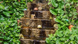 A stone water feature with cascading water, surrounded by lush green foliage. - Maison Tulum (Tulum)
