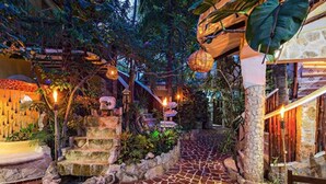 A stone pathway leading through a lush garden area with steps and hanging lanterns. - Maison Tulum (Tulum)