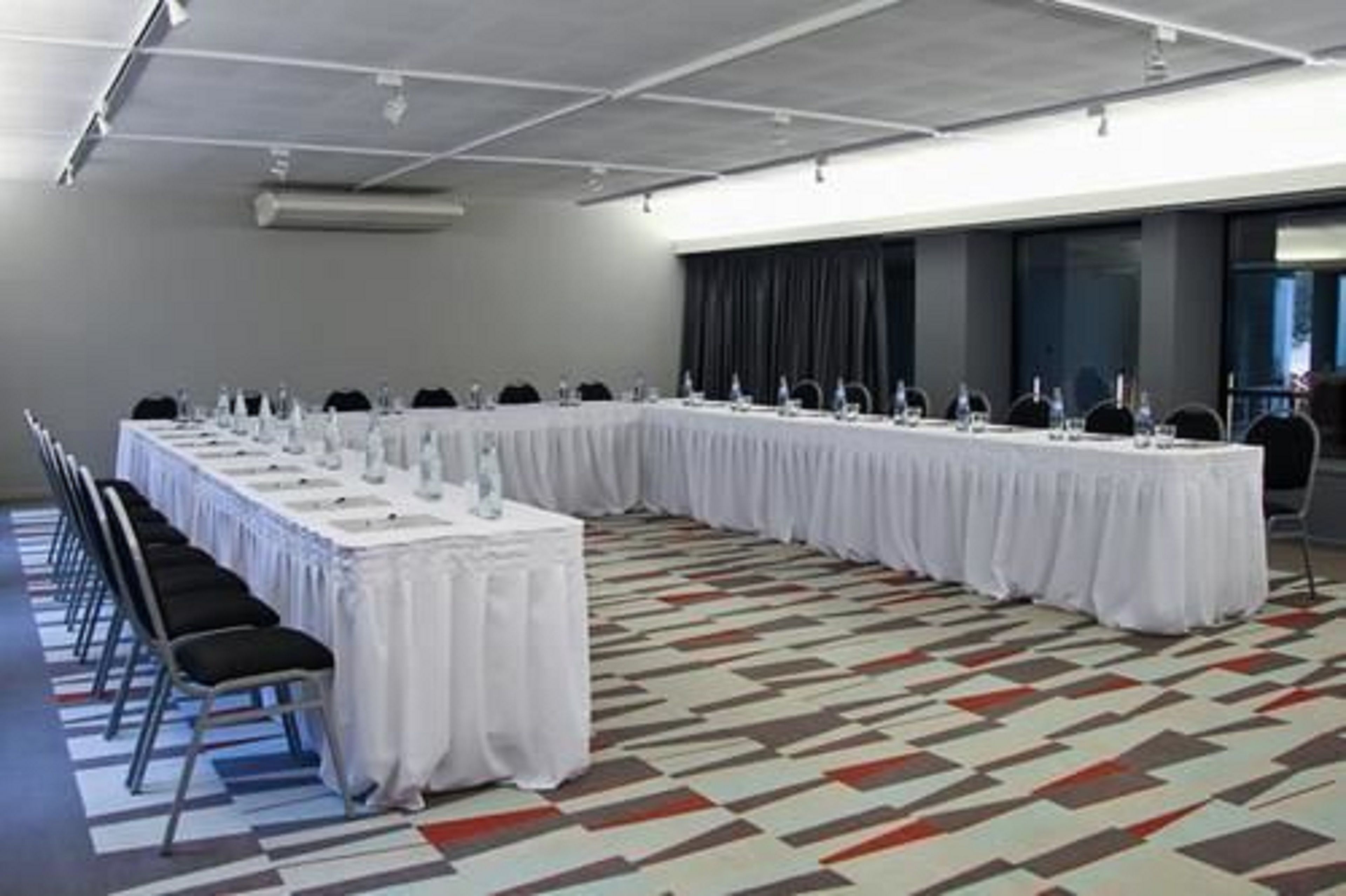 Una sala de conferències amb una taula llarga, cadires i una catifes amb dibuixos.