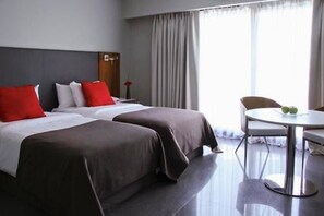 Une chambre d’hôtel avec deux lits, une table ronde et une chaise.