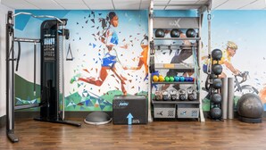 A gym with a variety of exercise equipment, including a weight rack, kettlebells, and a stationary bike. - Hampton Inn & Suites Richmond/Glenside (Richmond)
