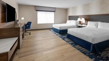 A hotel room with a flat-screen TV, a desk, two beds, a chair, and a window.