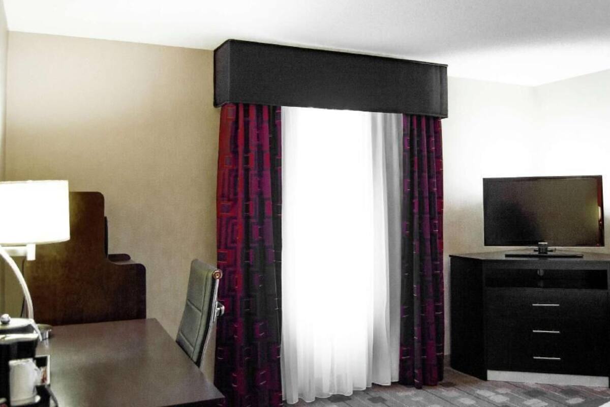 A hotel room with a bed, a TV, a desk, and a chair.