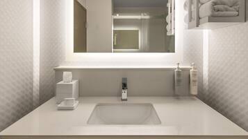 Un baño moderno con un espejo grande, un lavamanos y un perchero para toallas.