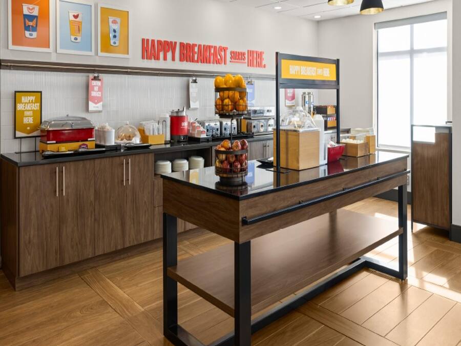 A breakfast area with a counter, a coffee machine, and a fruit display.