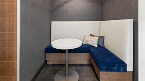 A modern seating area with a round table, a geometric light fixture, and patterned walls. - Hampton Inn & Suites Richmond/Glenside (Richmond)