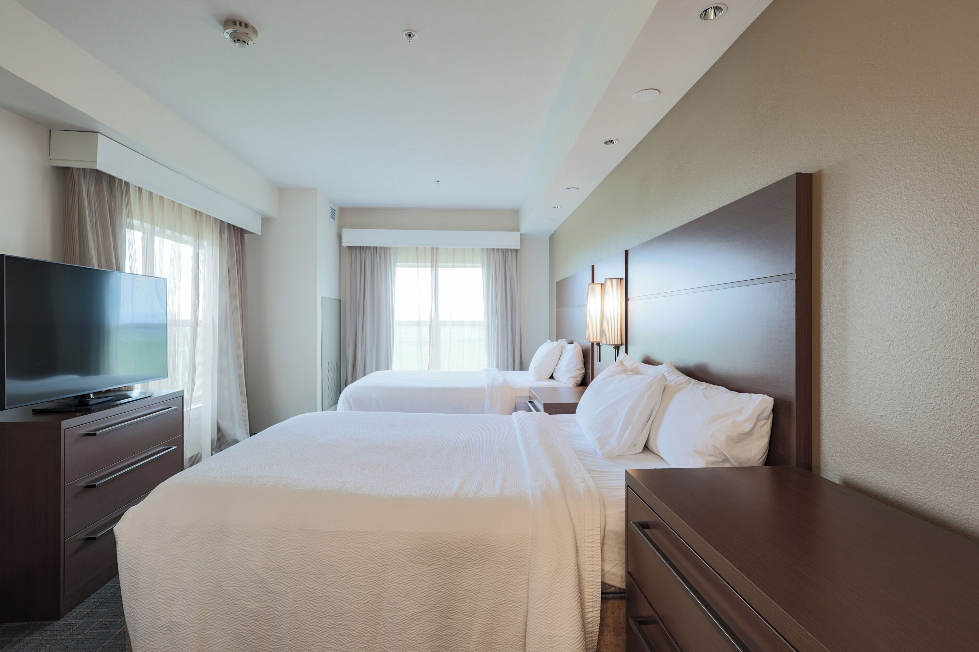 A hotel room with two beds, a TV, and a large window.