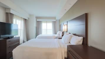 A hotel room with two beds, a TV, and a large window.