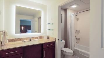 A bathroom with a vanity, a toilet, a shower, and a mirror.
