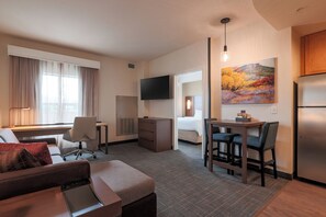 A hotel room with a sofa, a desk, a chair, a television, a painting, and a refrigerator. - Residence Inn by Marriott Helena (Helena)