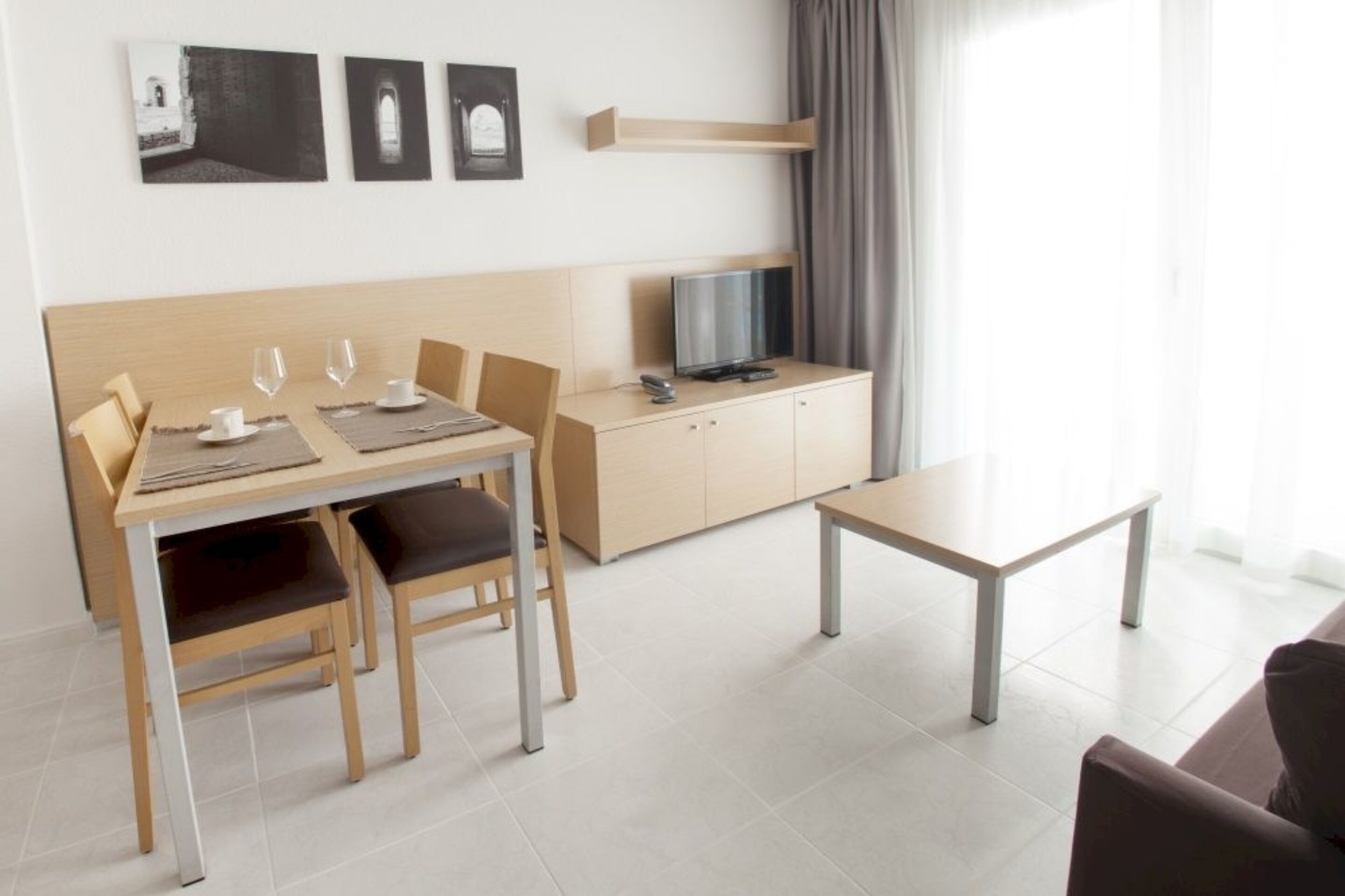 Une chambre d’hôtel moderne équipée d’une table à manger, de deux chaises, d’un téléviseur et d’un canapé.