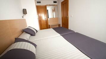 Ein Hotelzimmer mit Bett, Nachttisch, Spiegel und Tür.