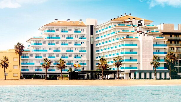 A beachfront hotel with multiple balconies, palm trees, and a clear view of the sea. - Aparthotel Acuazul (Peniscola)