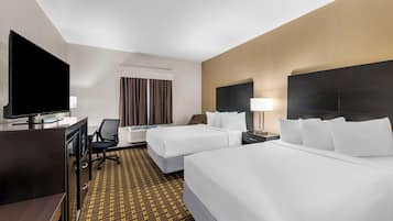 Quarto de hotel com duas camas, uma escrivaninha, uma TV e uma janela com cortinas.