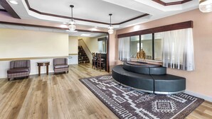A spacious living area with a wooden floor, a patterned rug, a built-in seating area, and a staircase leading to an upper level. - Best Western Halito Inn (Calera)