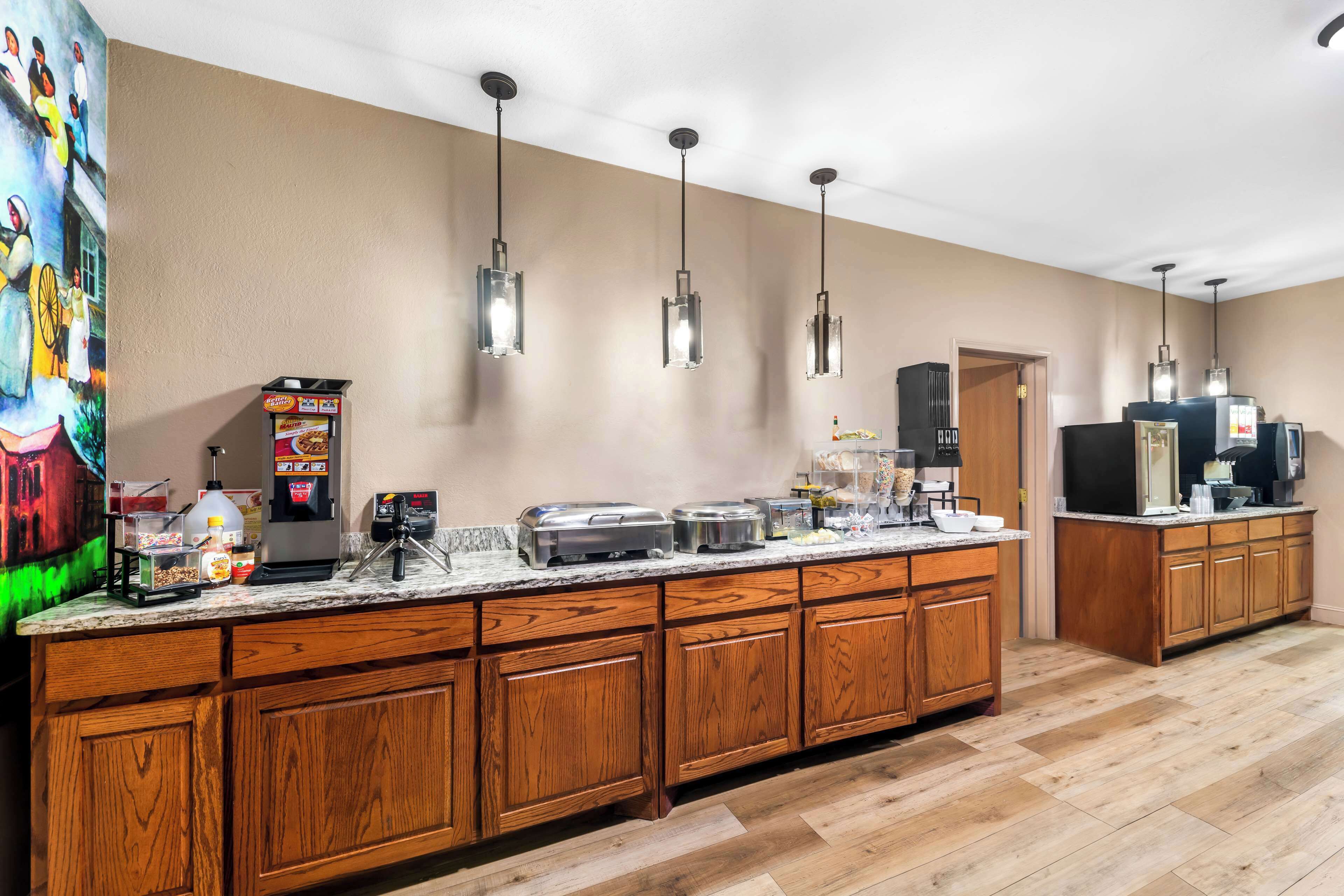 A kitchen with wooden cabinets, a marble countertop, and hanging pendant lights.