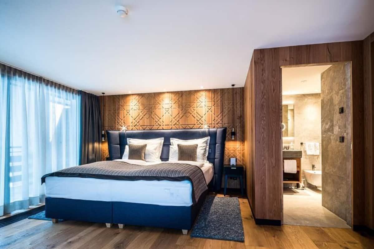 Une chambre à coucher moderne avec un grand lit, un mur recouvert de panneaux en bois et une vue sur la salle de bain.