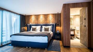 A modern bedroom with a large bed, wooden panel wall, and a view of the bathroom.