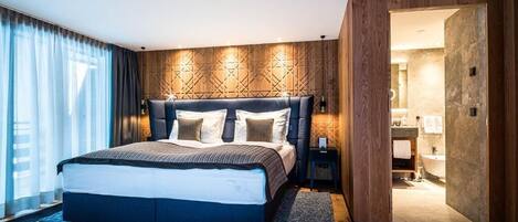Un dormitorio moderno con una cama grande, un panel de pared de madera y vistas al baño.