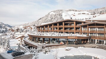 Un hotel moderno con fachada curva, varios balcones y un letrero que dice 'Grunbahta Dolomites'.